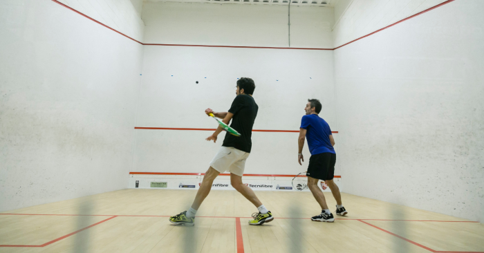 You Don’t Need To Hammer Your Opponent to Improve your level - two men playing squash on a squash court